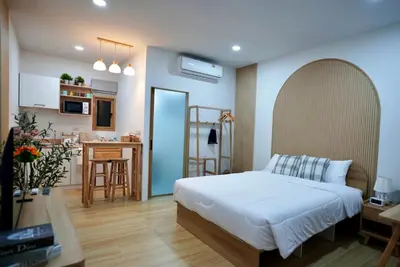 a bedroom with a white bed and a kitchen at The Cozy Haus Airport in Ban Muang Mai (1)