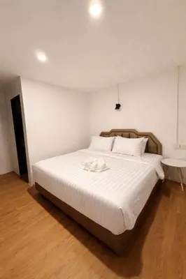 a bedroom with a large white bed with a wooden floor at HUG PHIPHI Resort in Phi Phi Don