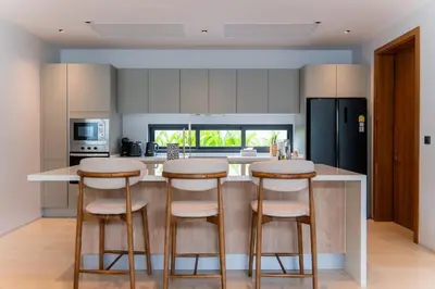 a kitchen with two bar stools and a counter top at UltraLuxury 4BDR pool villa Botanica Foresta in Ban Phru Champa