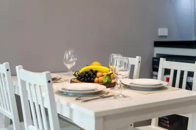 a white table with a bowl of fruit and wine glasses at Apartments 15 minutes walk from Bangtao Beach with a cinema in Phuket
