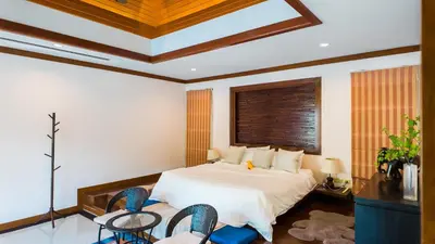 a bedroom with a bed with two chairs and a window at Genesis Elephant Villa in Rawai Beach