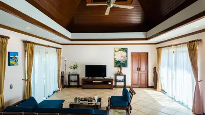 a living room with a blue couch and a tv at Genesis Elephant Villa in Rawai Beach