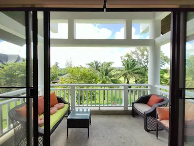 a screened in porch with two chairs and a table at Apartment 2 bedrooms in Allamanda in Laguna Phuket