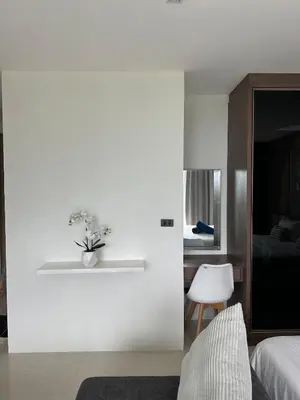 a bedroom with a white wall with a plant on a shelf at The Viva Patong Sea view and Mountain views in Patong Beach