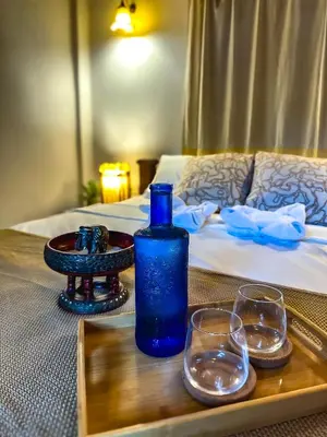 a table with a blue bottle and glasses on a bed at OASIS by Four Twenty in Chalong