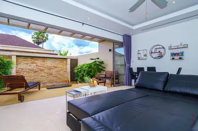a living room with a black couch and a patio at The Residence One-Bedroom Villa in Ban Thalat Choeng Thale