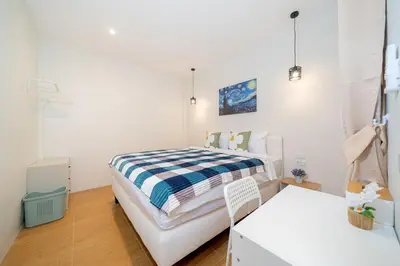a white bedroom with a bed and a table at Cozy Home in heart of Patong in Patong Beach