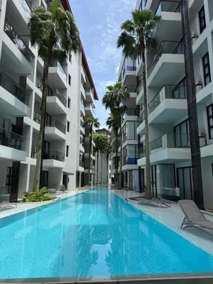 a swimming pool in front of a building with palm trees at Palmyrah Surin Apartments by Mill in Surin Beach