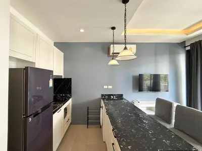 a kitchen with a black counter top and a refrigerator at Palmyrah Surin Apartments by Mill in Surin Beach