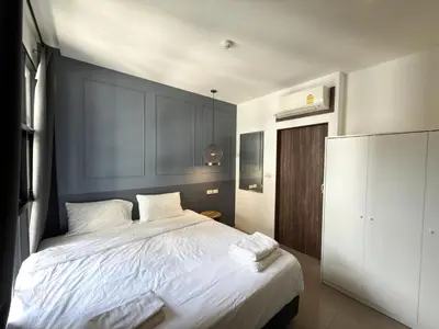 a bedroom with a large bed with white sheets at Palmyrah Surin Apartments by Mill in Surin Beach