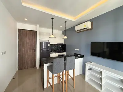 a kitchen with a bar with two chairs and a tv at Palmyrah Surin Apartments by Mill in Surin Beach