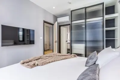 a bedroom with a large white bed and a flat screen tv at Family Deluxe close to Bang Tao Beach in Bang Tao Beach