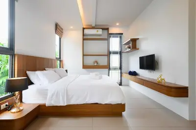 a bedroom with a large white bed and a tv at New Luxury Pool Villa Bangtao Phuket in Ban Pak Lak