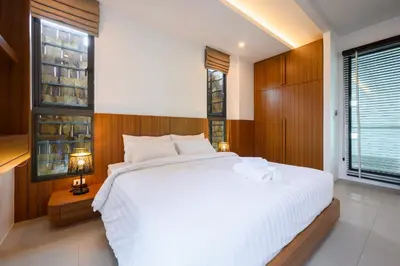 a bedroom with a large white bed and windows at New Luxury Pool Villa Bangtao Phuket in Ban Pak Lak