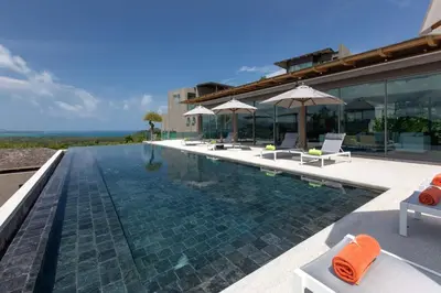 a swimming pool with chairs and umbrellas next to a building at Tropical Castle Villa in Phuket Town