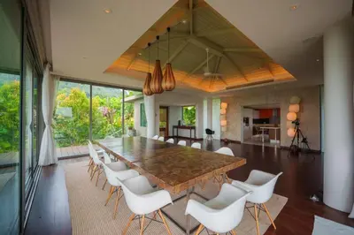 a large dining room with a large wooden table and white chairs at Tropical Castle Villa in Phuket Town