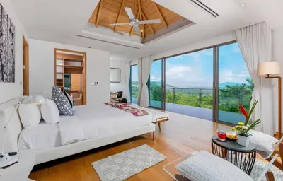 a bedroom with a white bed and a large window at Tropical Castle Villa in Phuket Town