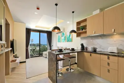 a kitchen with a counter and a living room at Stylish apartments in Calypso Garden condo, Sea View! in Rawai Beach