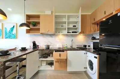 a kitchen with wooden cabinets and a washer and dryer at Stylish apartments in Calypso Garden condo, Sea View! in Rawai Beach