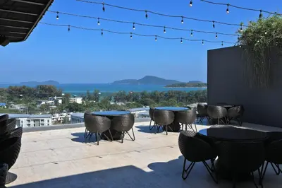 a patio with tables and chairs and a view of the water at Stylish apartments in Calypso Garden condo, Sea View! in Rawai Beach