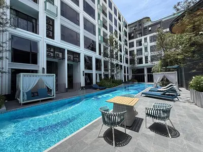 a swimming pool in a building with a table and chairs at New Apartment on the 1floor in The Proud Karon in Karon Beach