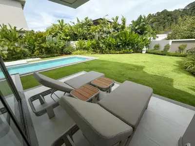 a patio with chairs and a pool and a yard at Lake View Landscape Modern villa Bang Tao in Ban Thalat Choeng Thale