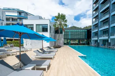 a swimming pool with lounge chairs and blue umbrellas at BlueSotel Krabi AoNang Beach in Ao Nang Beach
