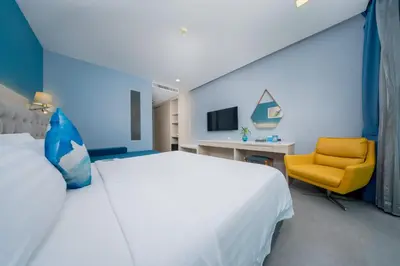 a bedroom with a white bed and a yellow chair at BlueSotel Krabi AoNang Beach in Ao Nang Beach