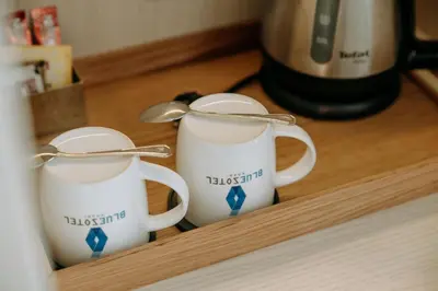 two white coffee mugs sitting on a wooden shelf at BlueSotel Krabi AoNang Beach in Ao Nang Beach