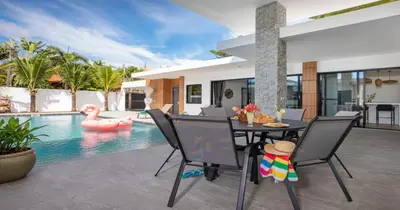 a dining room with a table and chairs next to a swimming pool at Stunning Pool Villa Curtis - 5 Bedrooms in the heart of Rawai in Rawai Beach