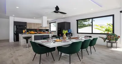a dining room and kitchen with a table and green chairs at Stunning Pool Villa Curtis - 5 Bedrooms in the heart of Rawai in Rawai Beach