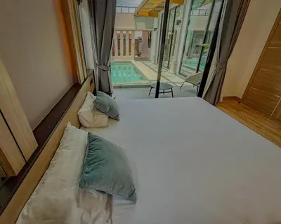 a bed with two pillows in a room with a pool at Holiday Villa 2-BR J10, Private Pool, Rawai Beach in Phuket Town