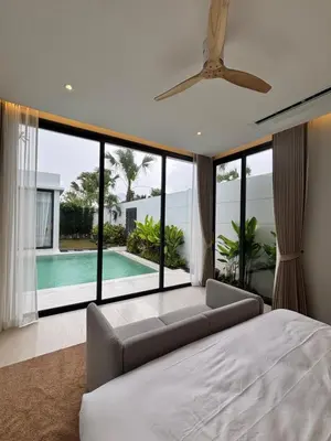 a bedroom with a bed and a couch and a pool at Phuket Moana Pool Villa in Ban Na Nai