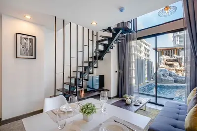 a living room with a spiral staircase and a table and chairs at Utopia Lofts by Sabai Sands in Nai Harn Beach