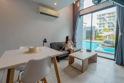 a woman sitting on a couch in a living room at Utopia Lofts by Sabai Sands in Nai Harn Beach