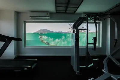 a gym with a view of the ocean through a window at Utopia Lofts by Sabai Sands in Nai Harn Beach