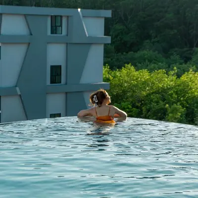 a woman in a swimming pool next to a building at Utopia Lofts by Sabai Sands in Nai Harn Beach