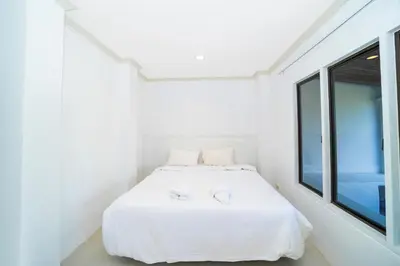 a white bedroom with a bed with two white towels at Patong Thai-style 4 Bedrooms Private Pool Sunset View Deck 6 Minutes to the Beach in Patong Beach
