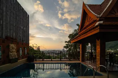 a swimming pool in front of a building with the sunset at Patong Thai-style 4 Bedrooms Private Pool Sunset View Deck 6 Minutes to the Beach in Patong Beach