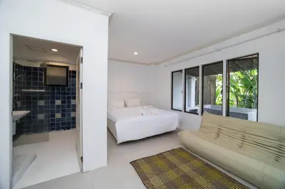 a bedroom with a bed and a tv and a couch at Patong Thai-style 4 Bedrooms Private Pool Sunset View Deck 6 Minutes to the Beach in Patong Beach