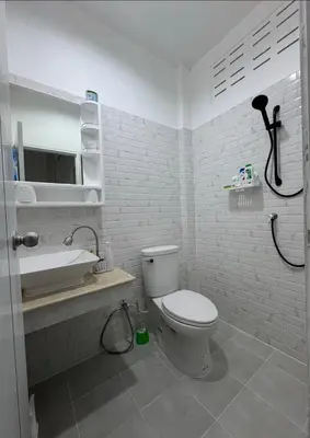 a white bathroom with a toilet and a sink at Palai House in Ban Na Bon