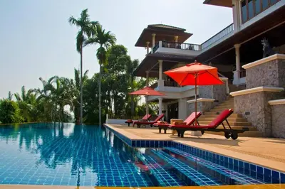 a swimming pool with chairs and an umbrella next to a house at Villa Oriole - Luxury Pool Villa in Layan Beach