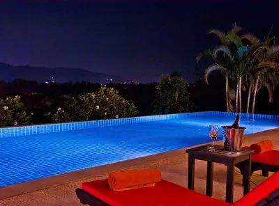 a swimming pool at night with a table and a wine glass at Villa Oriole - Luxury Pool Villa in Layan Beach