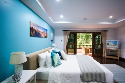 a bedroom with a large bed with a blue wall at Villa Oriole - Luxury Pool Villa in Layan Beach