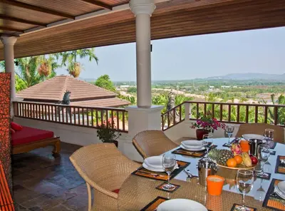 a dining room with a table and chairs on a balcony at Villa Oriole - Luxury Pool Villa in Layan Beach