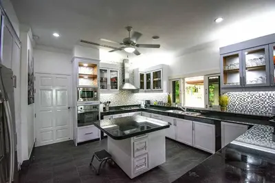 a kitchen with white cabinets and a ceiling fan at Villa Oriole - Luxury Pool Villa in Layan Beach