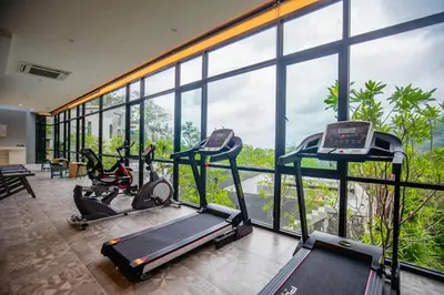a gym with two exercise bikes in a room with windows at Design Duplex Pavillion 2 BR Natural Park P11 in Kamala Beach
