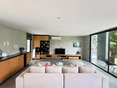 a living room with a white couch and a kitchen at Design Duplex Pavillion 2 BR Natural Park P11 in Kamala Beach