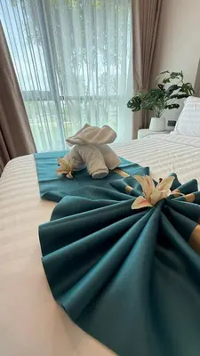 a bed with a blue blanket and two lilies on it at Space Cherngtalay Condo in bangtao by sahana in Bang Tao Beach