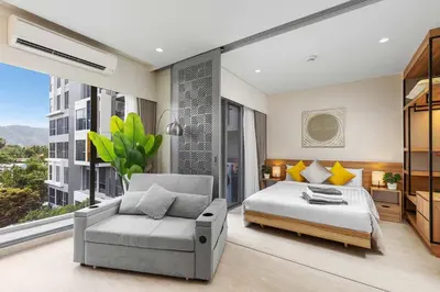 a bedroom with a bed and a chair and a window at Laguna Lakeside BangTao Phuket in Bang Tao Beach
